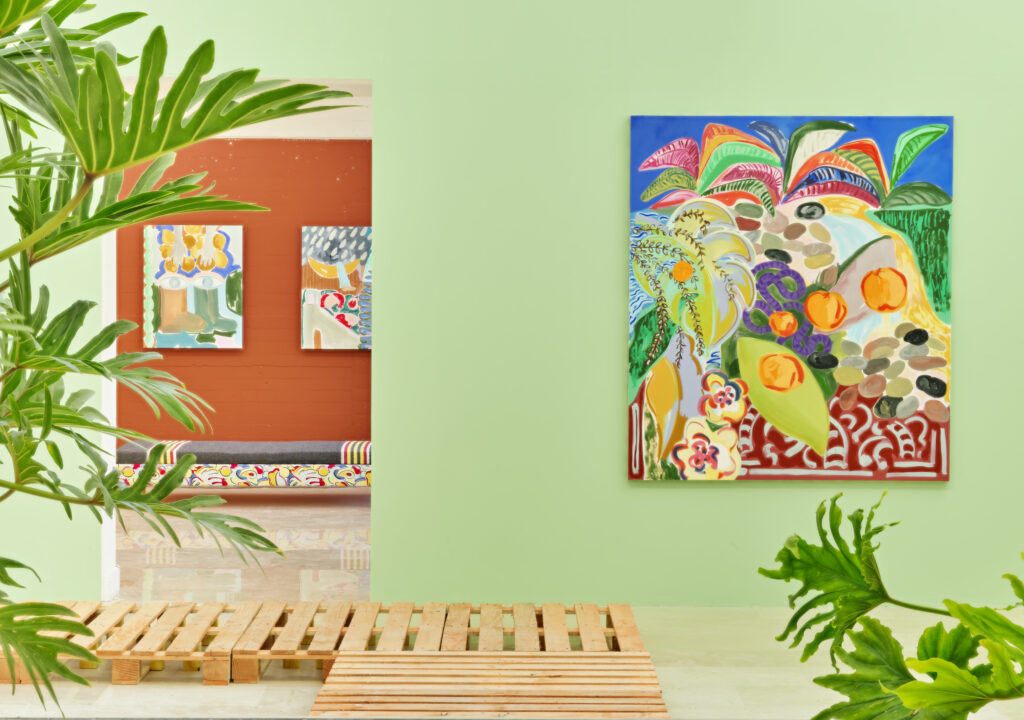 peintures sur toile accrochées sur murs peints, plantes vertes et passerelles en bois de palettes