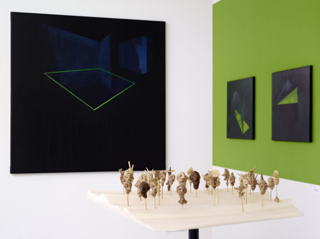 Une sculpture sur socle avec 3 tableaux au mur
