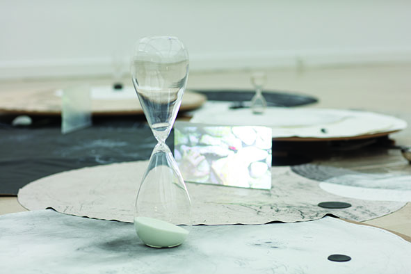 installation avec sablier, dessin, vidéo et grand cercle de contreplaqué