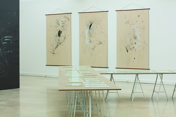 une table présentant des dessins et trois grandes bannières au mur