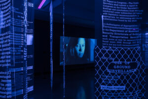 installation avec écran vidéo et textes muraux plongée dans une lumière bleue