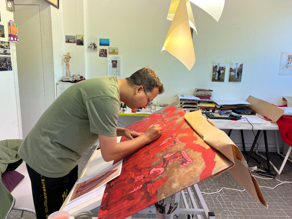 Mohsin Taasa penché sur sa peinture rouge dans son atelier