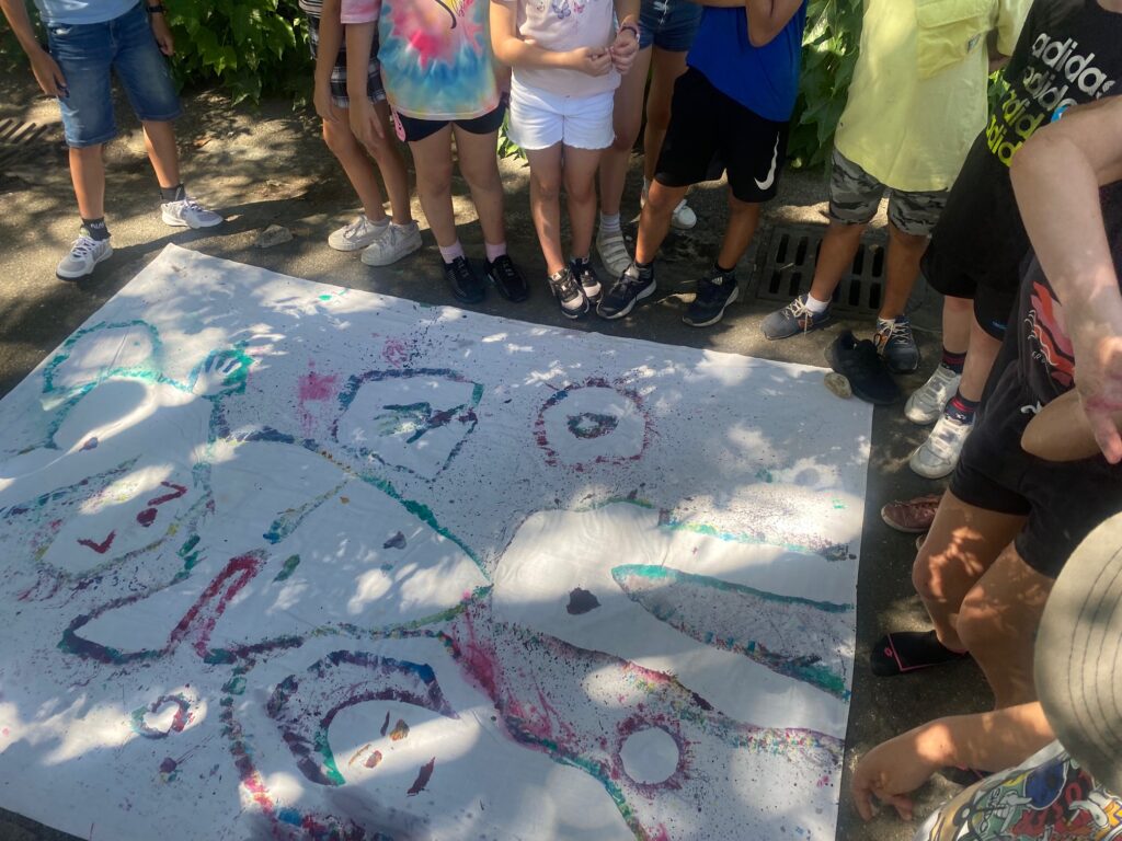 Une peinture posée au sol, des enfants posés autour